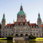 Das Neue Rathaus in Hannover mit Spiegelung im davorliegenden Teich an einem sonnigen Tag.