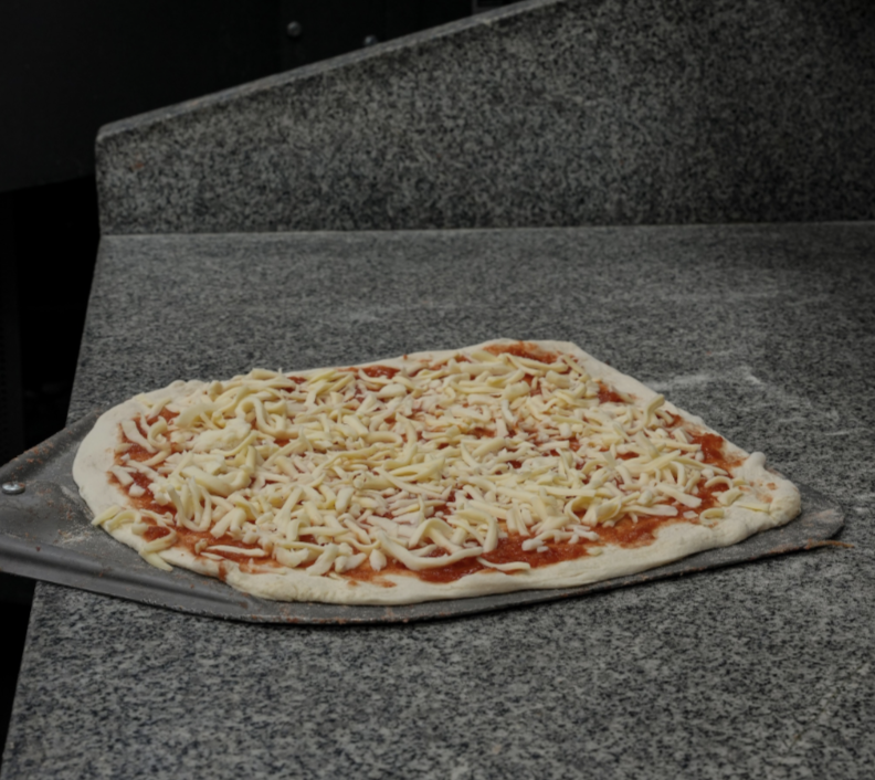 Ausgerollter Pizzateig mit Tomatensauce und Käse belegt bei 450 Folded Dortmund