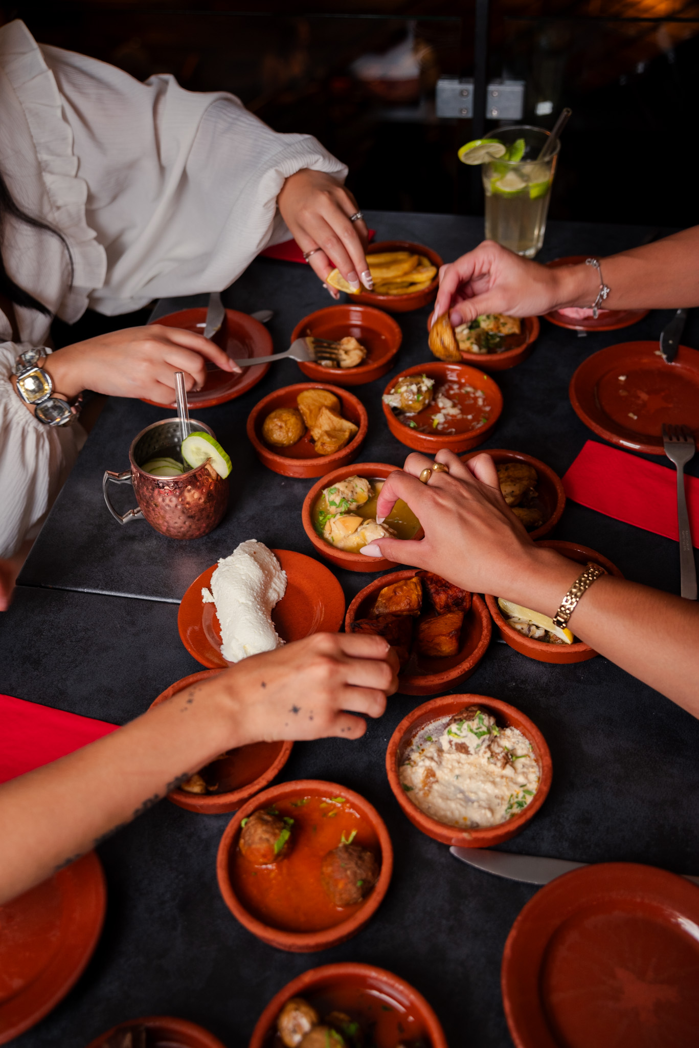 Mehrere Hände greifen zu verschiedenen Tapas auf einem reich gedeckten Tisch bei Tapas & More Dortmund