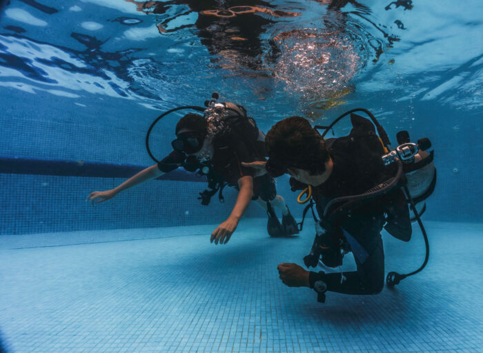 Teilnehmer des Scuba Diver Kurses führen eine Übung zur Tarierung und Fortbewegung am Beckenboden durch – Tauchcenter Wuppertal
