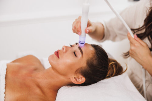 Frau bei moderner Hydrafacial-Behandlung mit Lichttherapie im Kosmetikstudio
