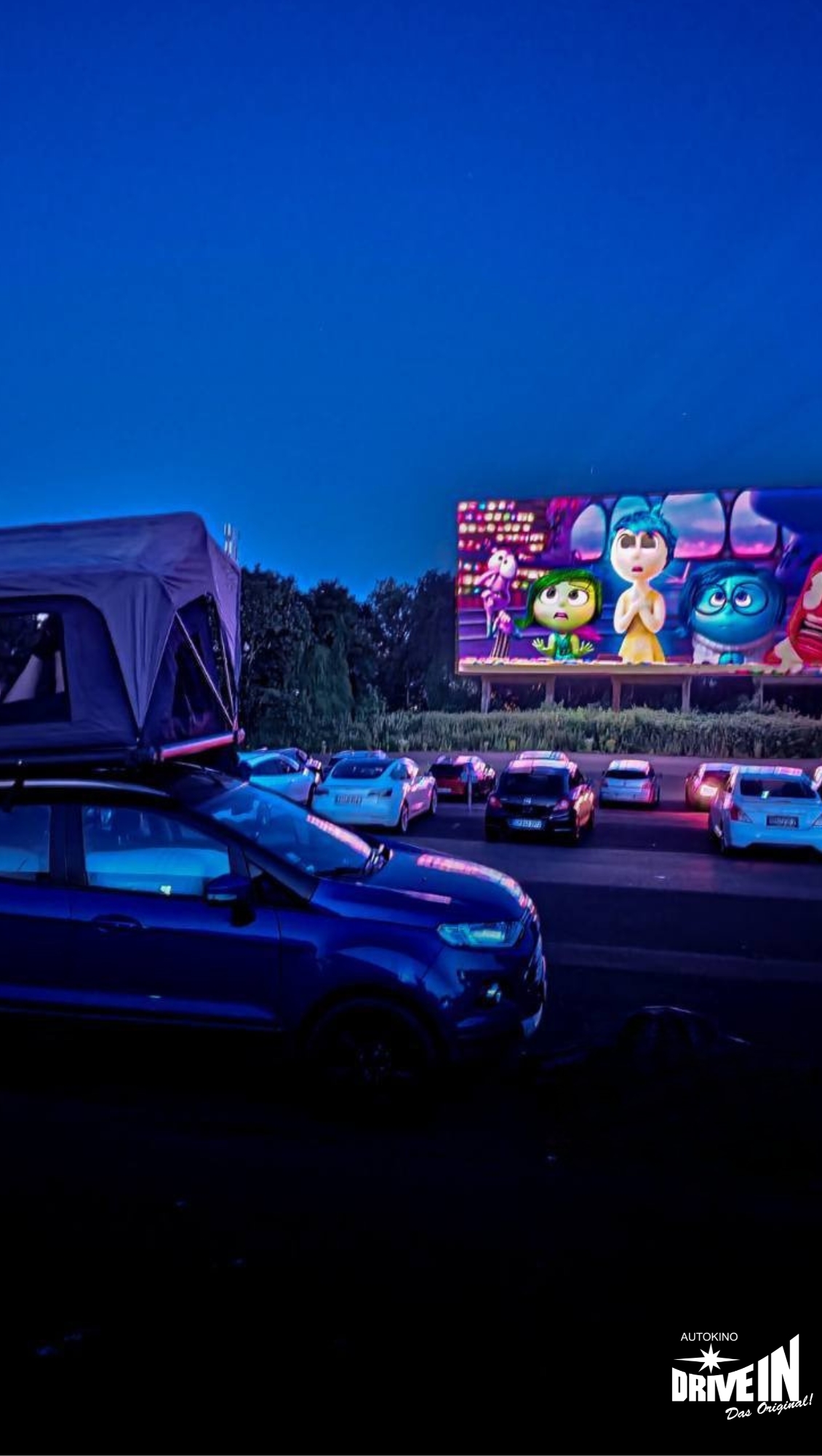 Abendliche Vorstellung eines Animationsfilms im Autokino Essen mit Fahrzeugen und Dachzelt