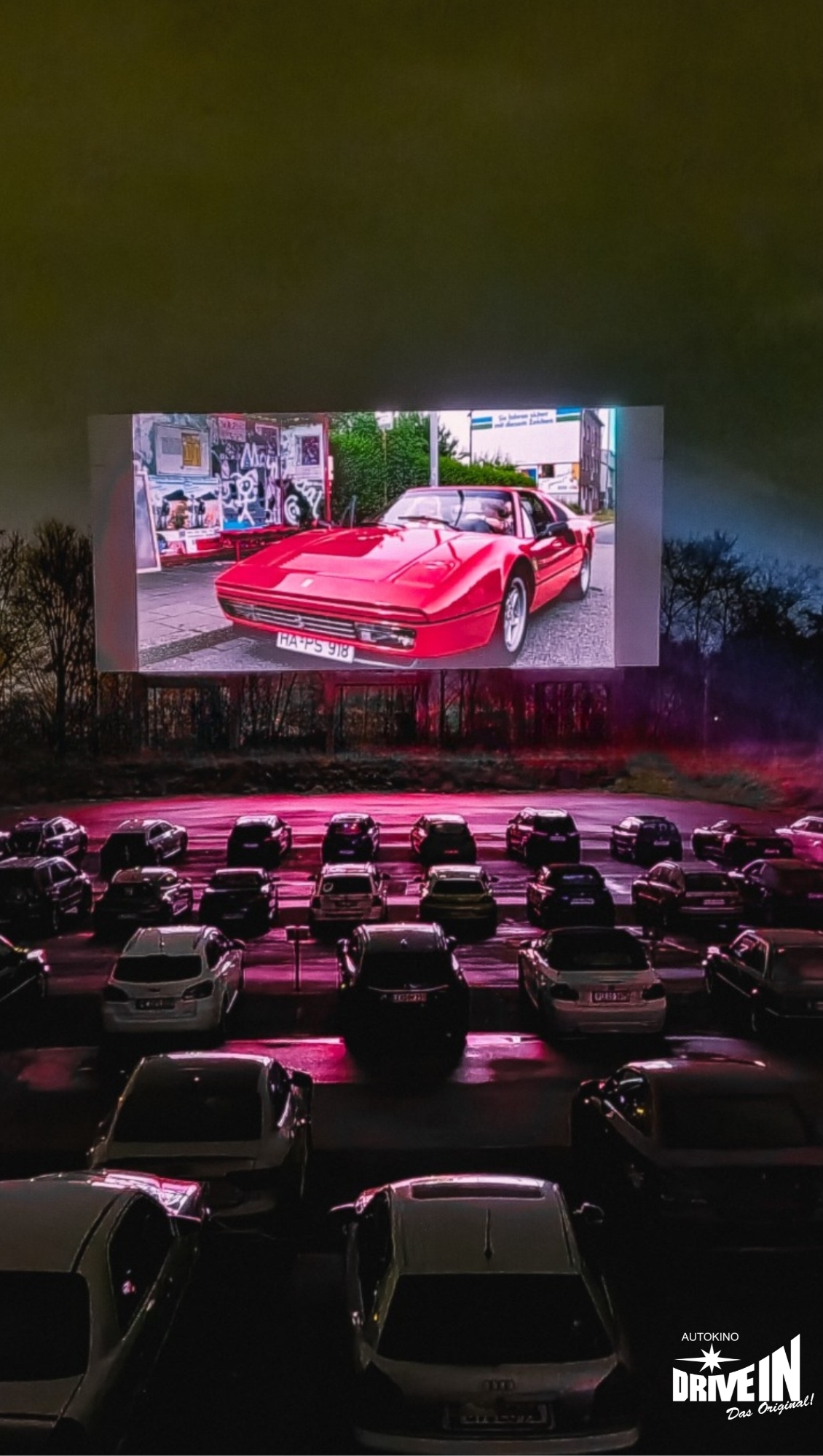 Szene mit rotem Sportwagen auf der Leinwand im Autokino Essen bei Nacht
