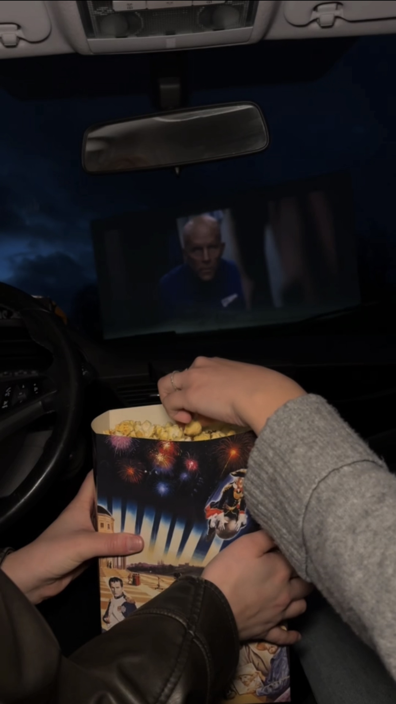 Hände greifen nach Popcorn aus einer Tüte während der Filmvorführung im Auto im Autokino Essen