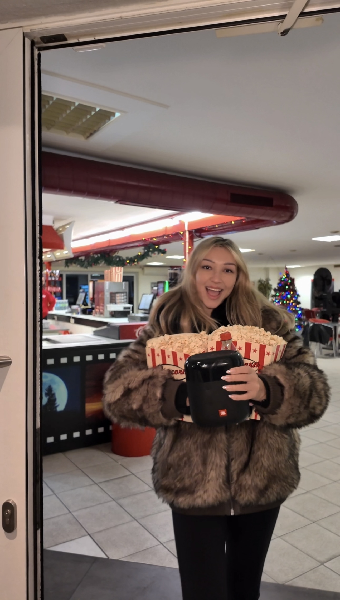 Frau lächelt und hält eine große Tüte Popcorn im Autokino Essen, vor dem Kioskbereich