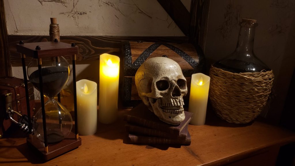 Totenschädel mit Kerzen und alter Truhe in mystischer Escape Room Kulisse