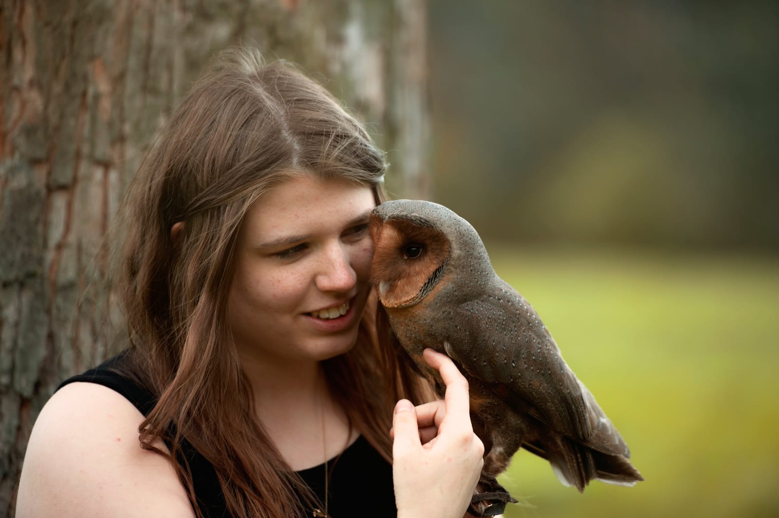 Junge Frau hält einen kleinen Greifvogel bei der Falknerei Skyhunters in Frechen und lächelt ihn an