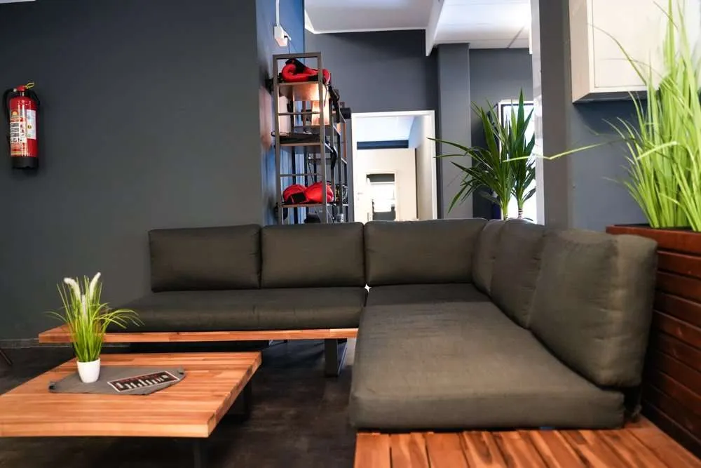 Moderner Loungebereich mit grauem Sofa und Holztisch im Fitness Wellness Loft Schleiden