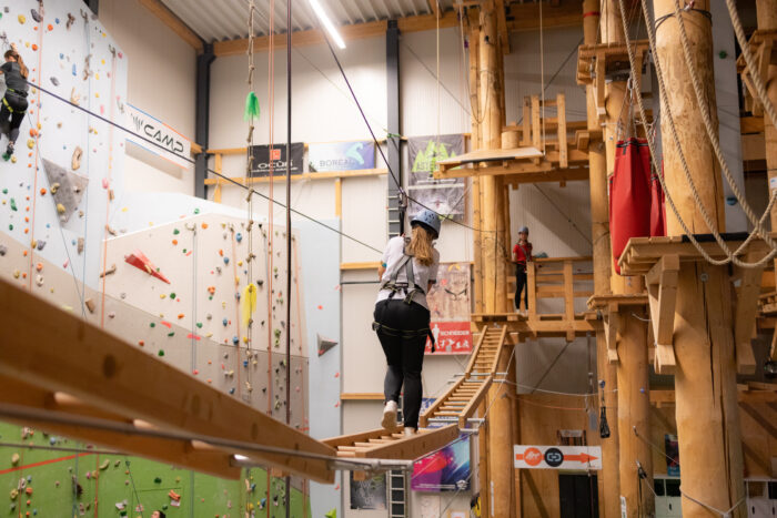 Person überquert einen Balancierparcours in der Freizeitwelt Sauerland, während sie auf einem Seil zwischen Kletterwänden balanciert