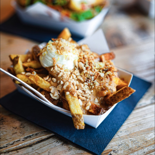 Kreativ angerichtete Pommes in einer Schale, serviert auf einem Holzbrett in der Frittenküche Dortmund