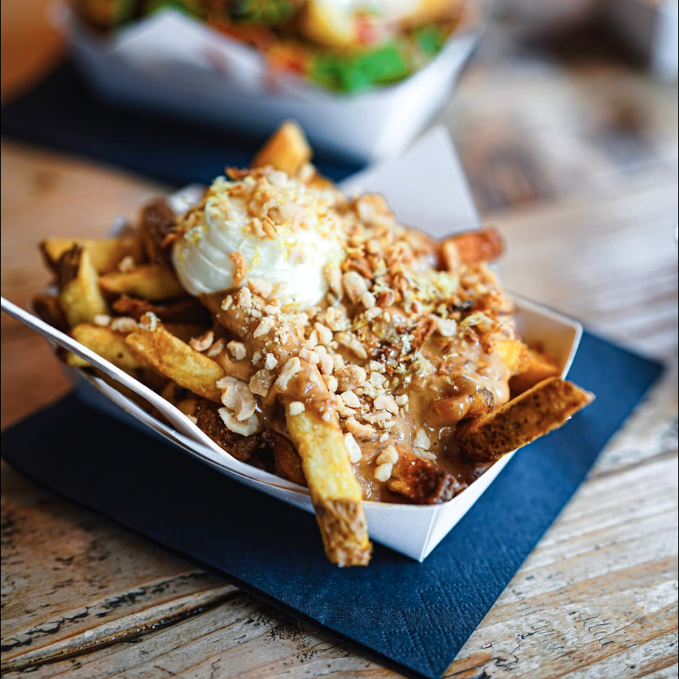 Kreativ angerichtete Pommes in einer Schale, serviert auf einem Holzbrett in der Frittenküche Dortmund