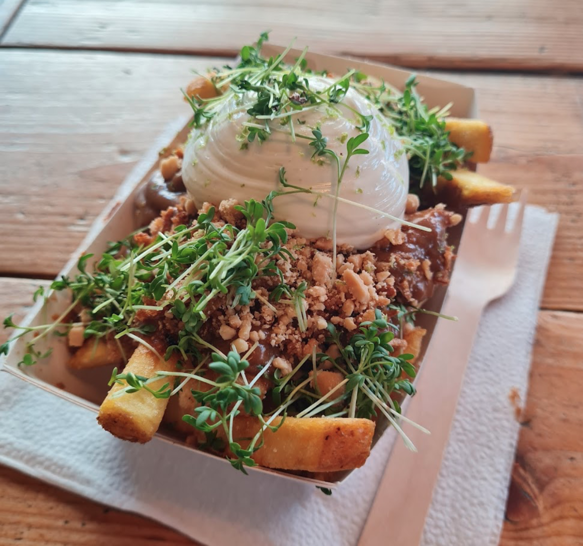 Pommes mit Burrata, Kresse und herzhaftem Topping in einer Schale auf Holztisch serviert