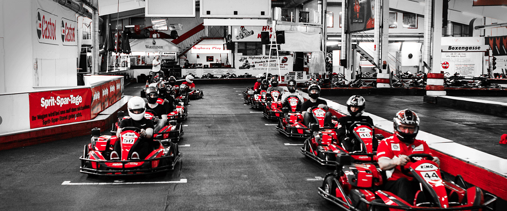 Mehrere Fahrer in roten Karts beim Start auf der Indoorbahn von Highway Kart Racing Dortmund