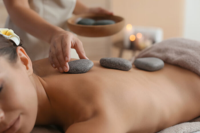 Wellnessbehandlung mit warmen Steinen auf dem Rücken im Rahmen einer Hot-Stone-Massage