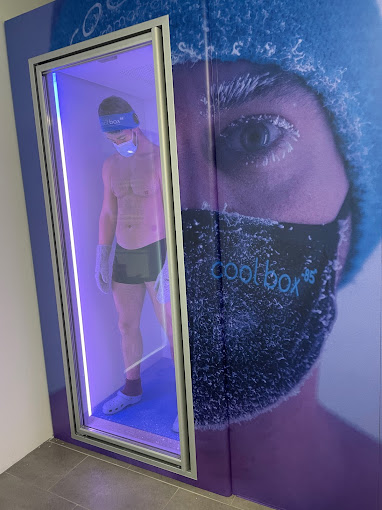 Mann in Shorts und Mütze steht in der beleuchteten Kryokammer der Coolbox Essen