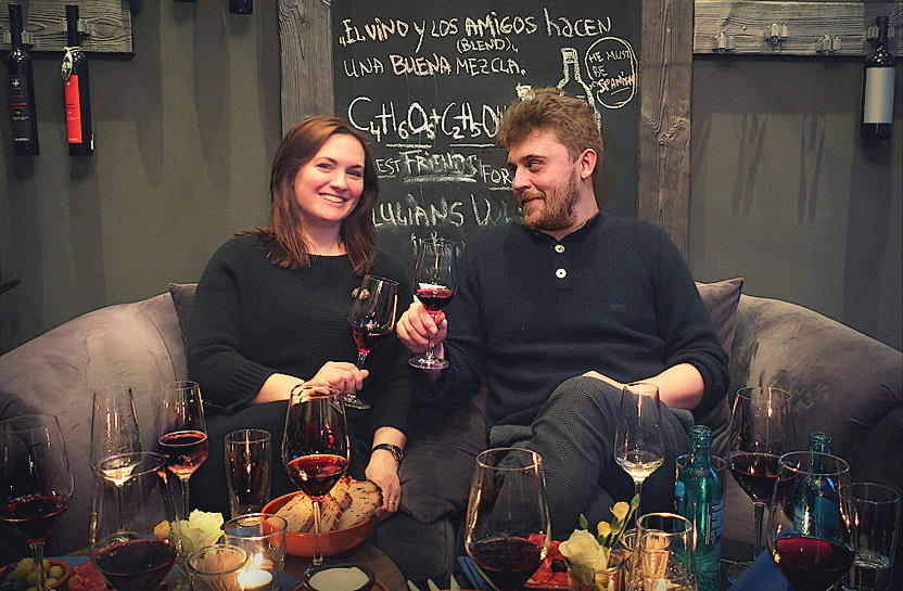 Paar beim Anstoßen mit Rotwein in gemütlicher Atmosphäre der Weinbar
