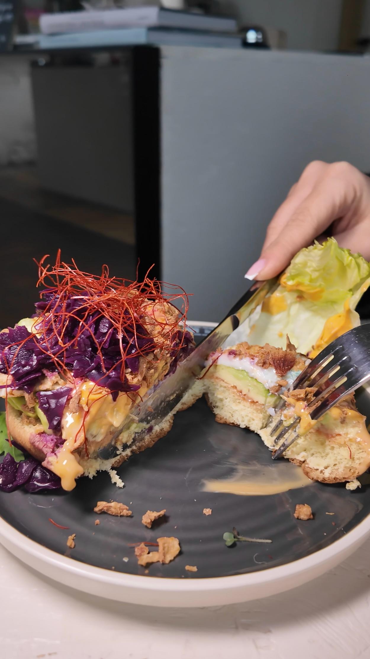Ein Burger bei LALA Smashburger Frankfurt wird mit Messer und Gabel angeschnitten