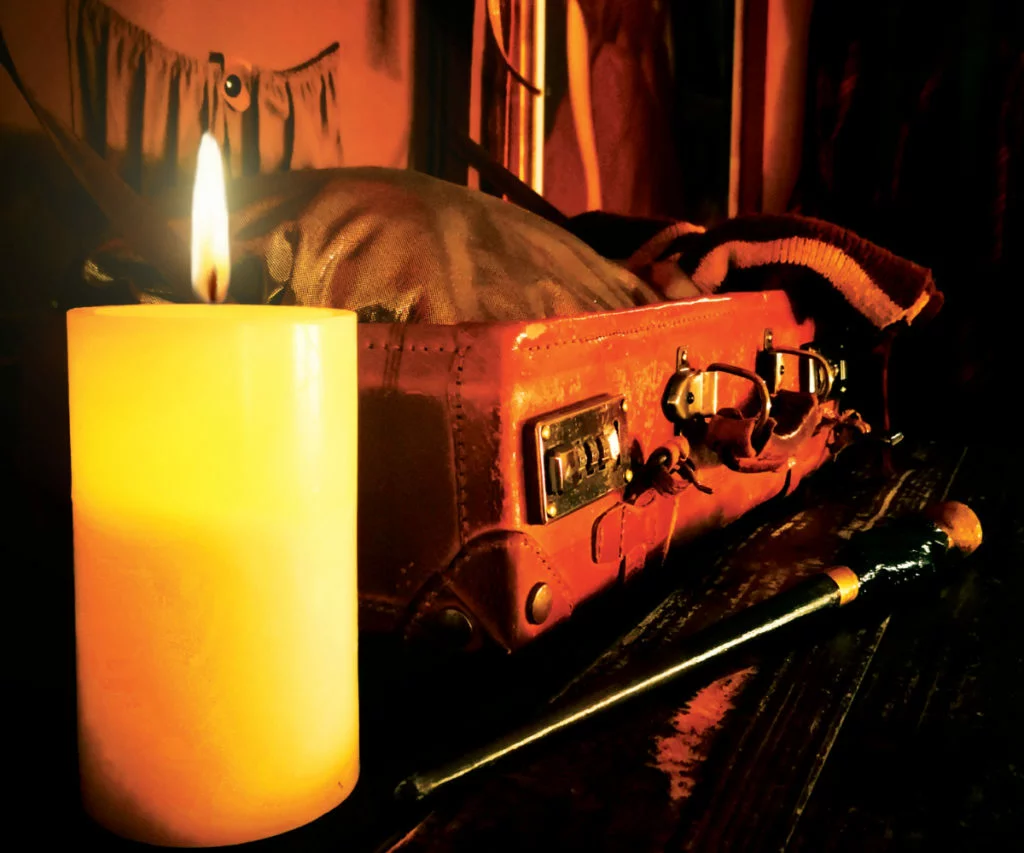 Kerze, alter Koffer und Zauberstab in stimmungsvoller Kulisse im Rätselraum Ruhrpott in Bochum