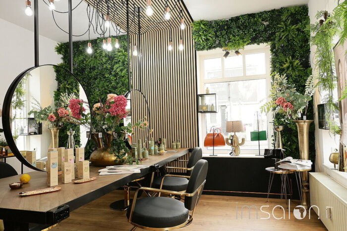 Eleganter und stilvoll dekorierter Innenraum von Ricci Hair & Beauty in Köln mit Pflanzenwand und modernen Friseurstühlen