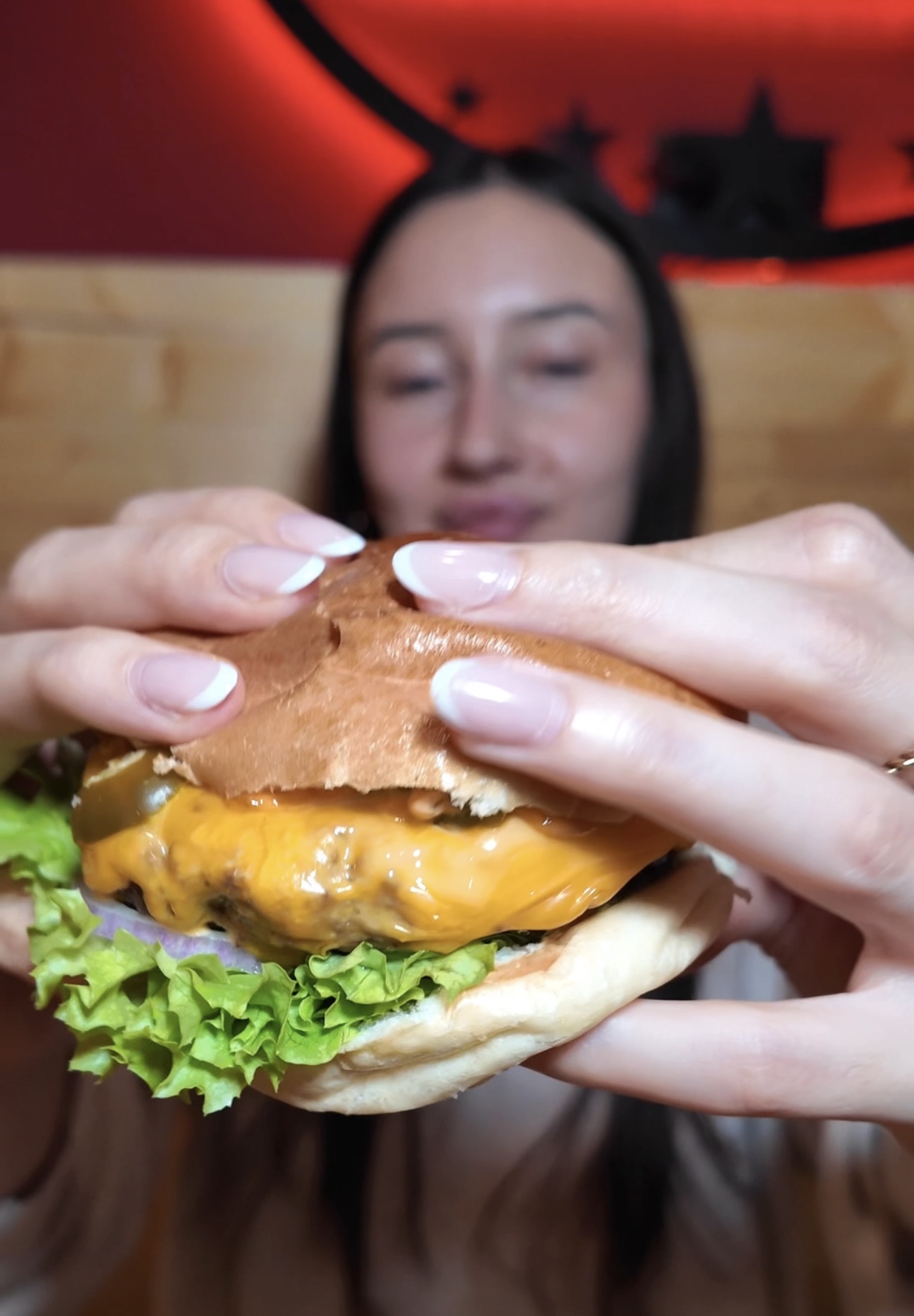 Frau hält einen frisch zubereiteten Burger im Rn Beef Moers und bereitet sich darauf vor, ihn zu genießen