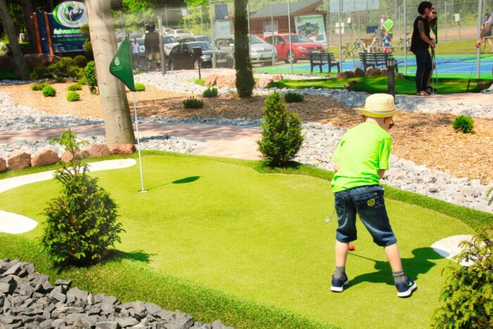Junge mit Strohhut spielt Adventure Golf im Sport- und Freizeitpark Limburg-Linter bei sonnigem Wetter