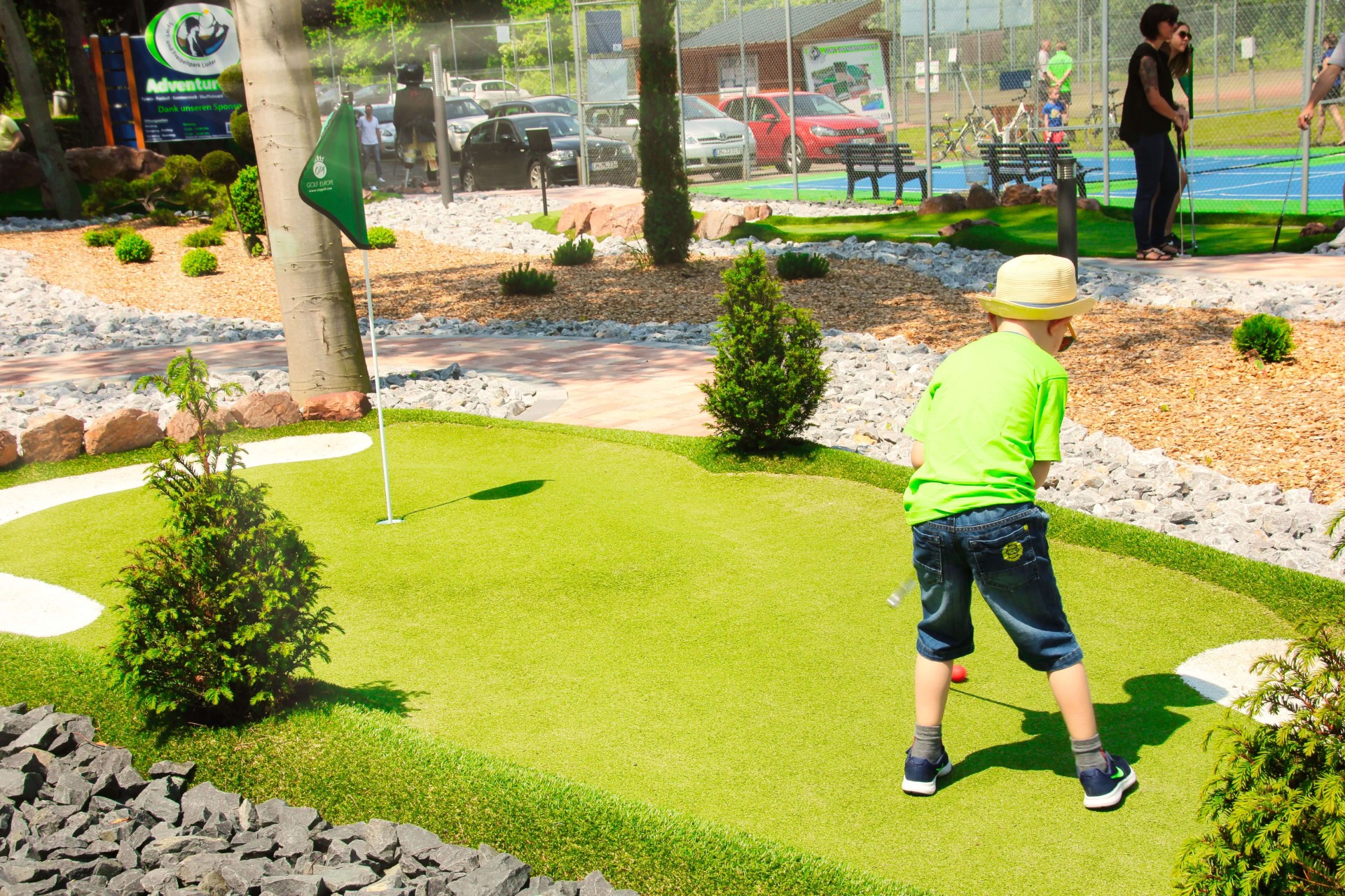 Junge mit Strohhut spielt Adventure Golf im Sport- und Freizeitpark Limburg-Linter bei sonnigem Wetter