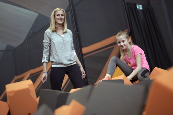 Mutter und Kind stehen auf einem Trampolin im Sprungwerk Hagen und spielen mit den Schaumstoffblöcken