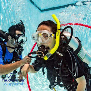 Tauchlehrer begleitet Teilnehmerin beim Schnuppertauchen im Pool des Tauchcenters Wuppertal mit kompletter Tauchausrüstung