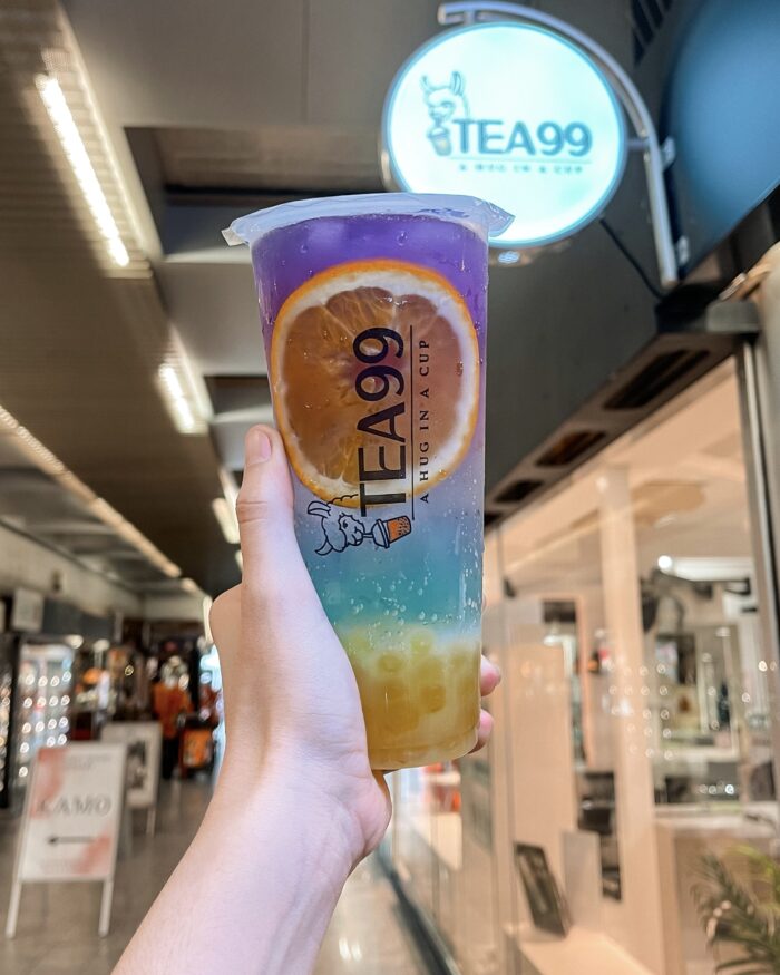 Farbintensives Bubble-Tea-Getränk mit Orangenscheibe von Tea99 Frankfurt, vor dem Geschäft gehalten