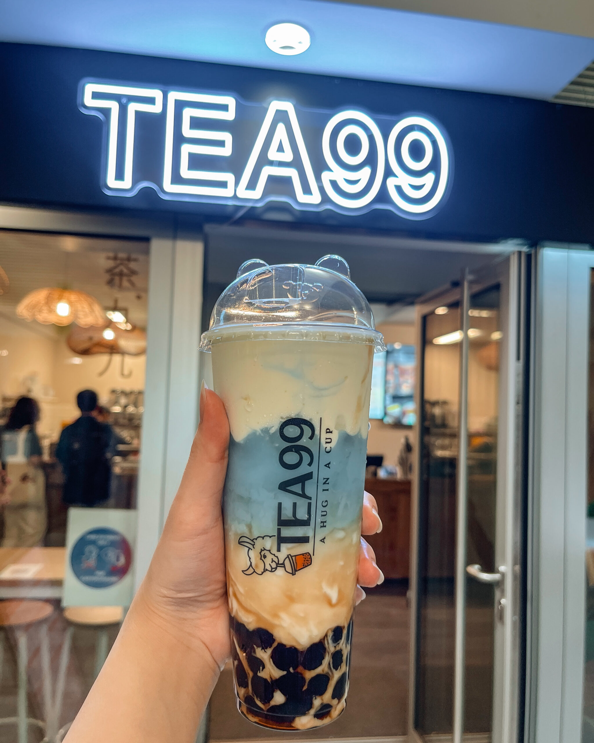 Farbintensiver Bubble Tea mit Orangenscheibe von Tea99 Frankfurt, serviert auf einem Holztisch im Laden