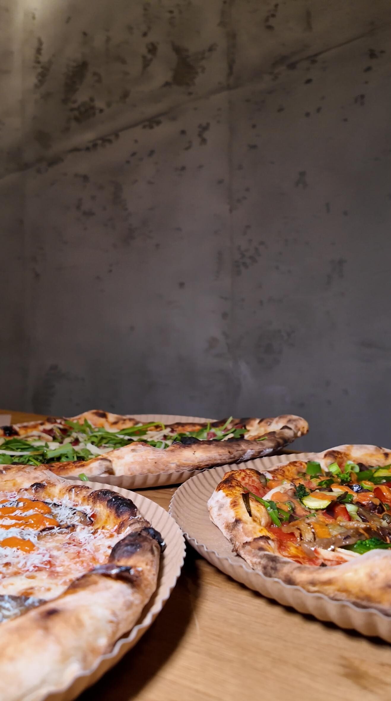 Frisch gebackene Pizza-Variationen mit knusprigem Rand, belegt mit Rucola, Gemüse und cremigem Käse bei Zampano To Go Frankfurt