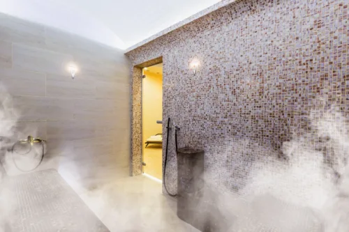 Stimmungsvoll beleuchtetes Dampfbad mit marmorierten Wänden und Wasserschale im Argan Garden Hamam Düsseldorf