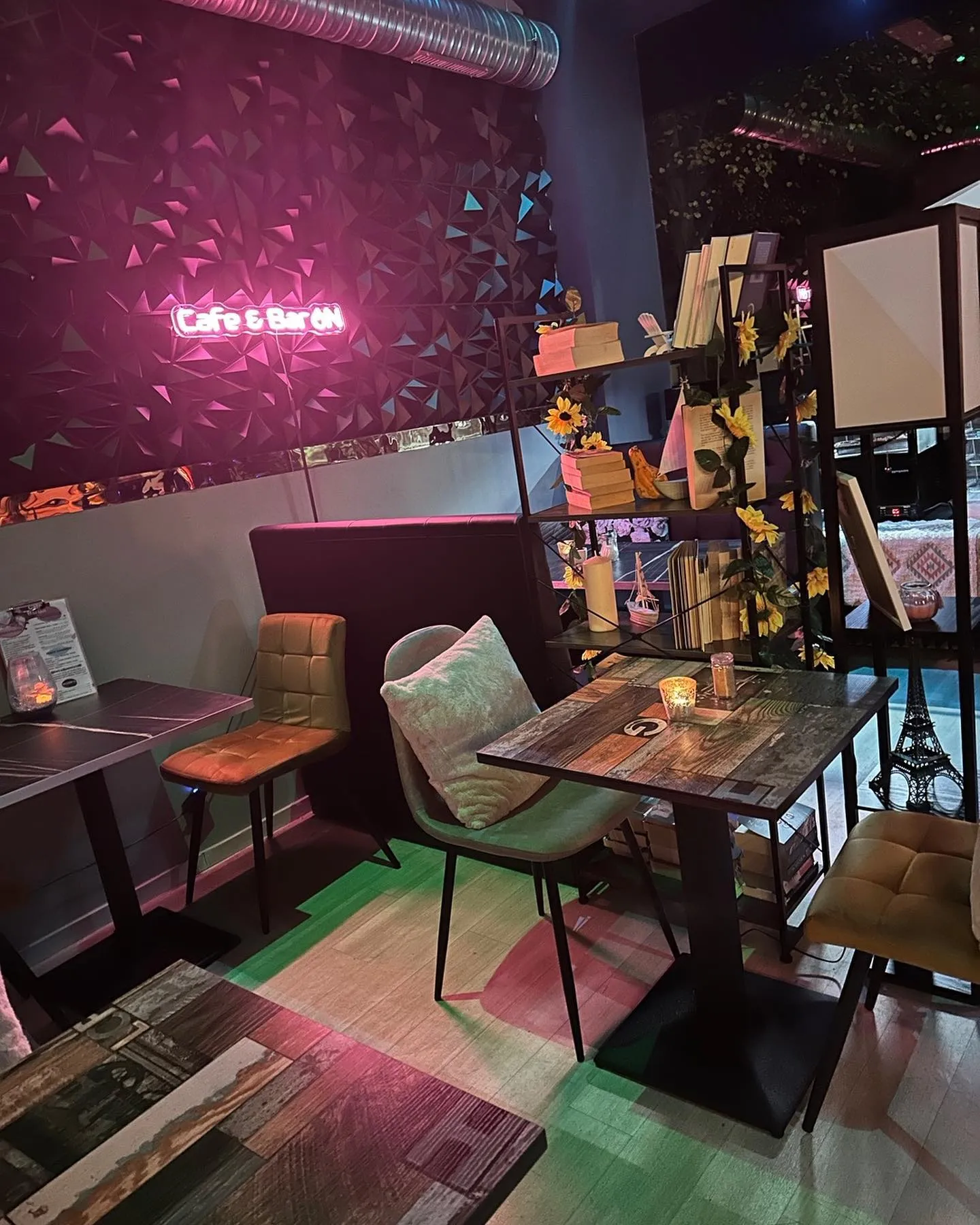 Gemütlicher Innenbereich der Café BarON Frankfurt mit bunten Teppichen, Retro-Möbeln, Deko-Regalen und pinkem Neon-Schriftzug „Life is for us“ an der Wand