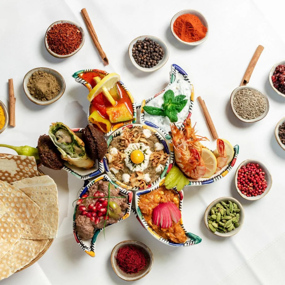 Farbenfroh angerichtete persische Vorspeisenplatte in sternförmigem Geschirr, umgeben von Gewürzen und Fladenbrot im Shiraz Restaurant Darmstadt