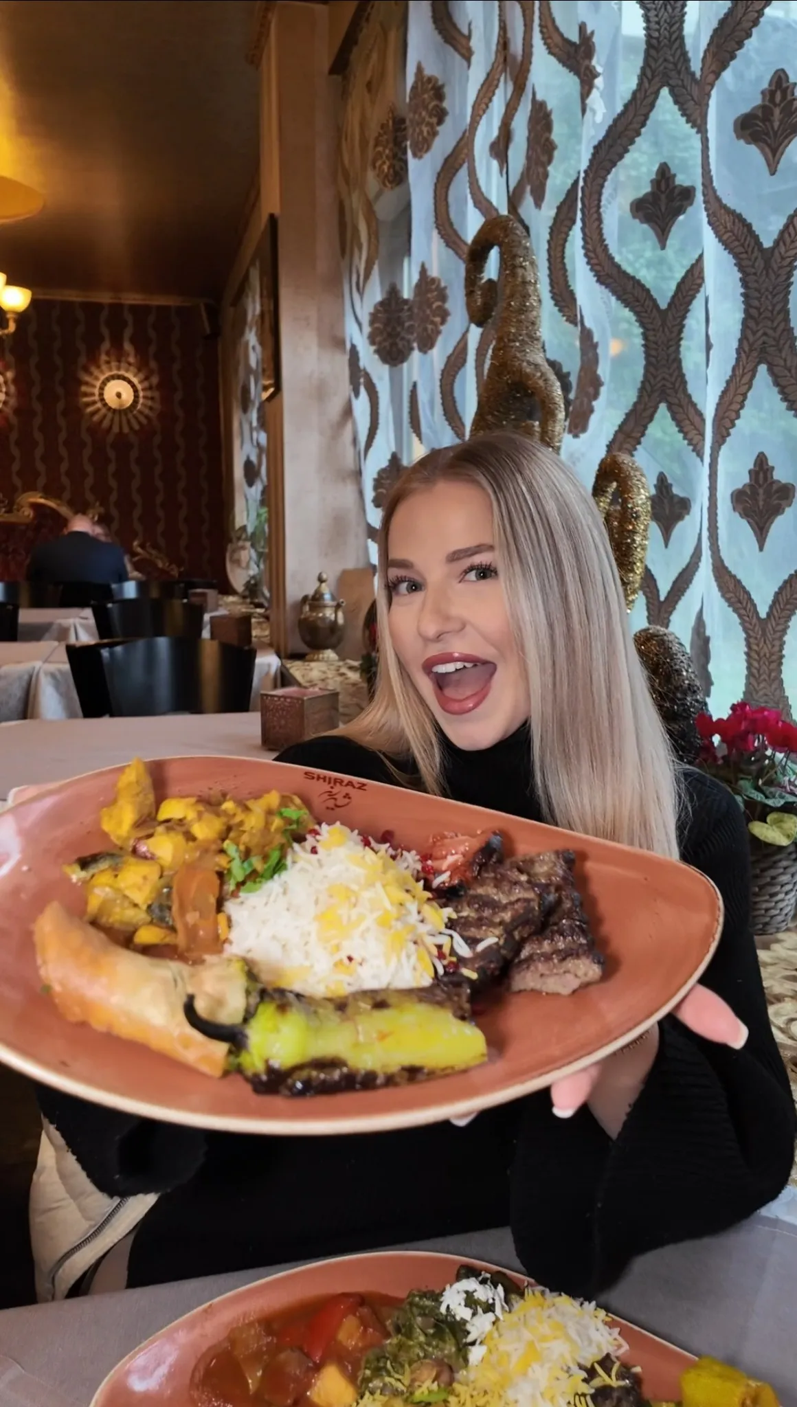 Frau hält eine große persische Grillplatte mit Reis, gegrilltem Fleisch und Gemüse im Restaurant Shiraz