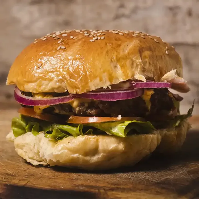 Hausgemachter Burger mit Sesam-Bun, Salat, Tomate, roten Zwiebeln und saftigem Patty im GODFATHER American Restaurant & Bar Wiesbaden