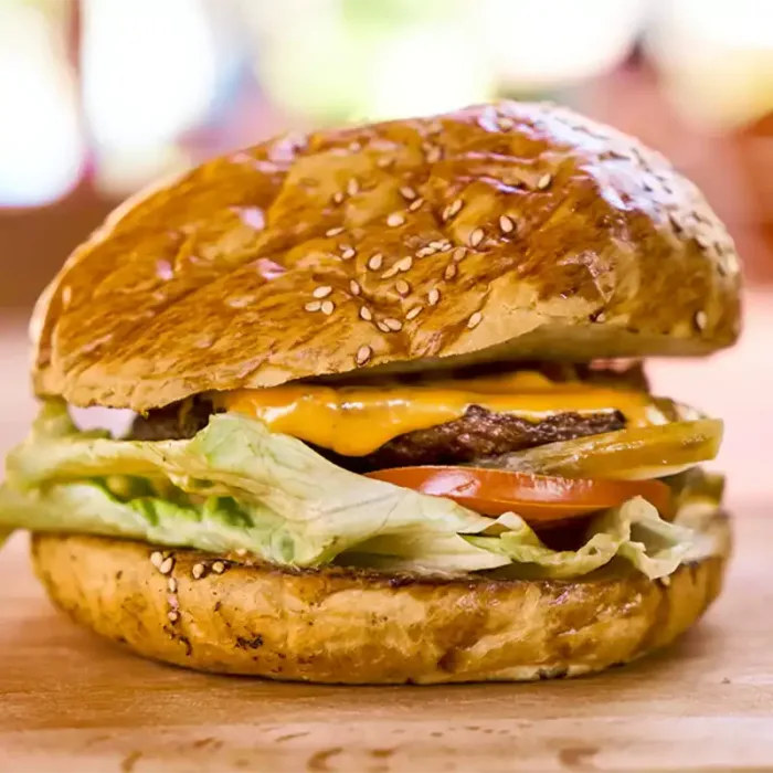 Frisch zubereiteter Cheeseburger mit Sesam-Bun, Cheddar, Rindfleischpatty, Tomate und Salat im GODFATHER American Restaurant & Bar Wiesbaden