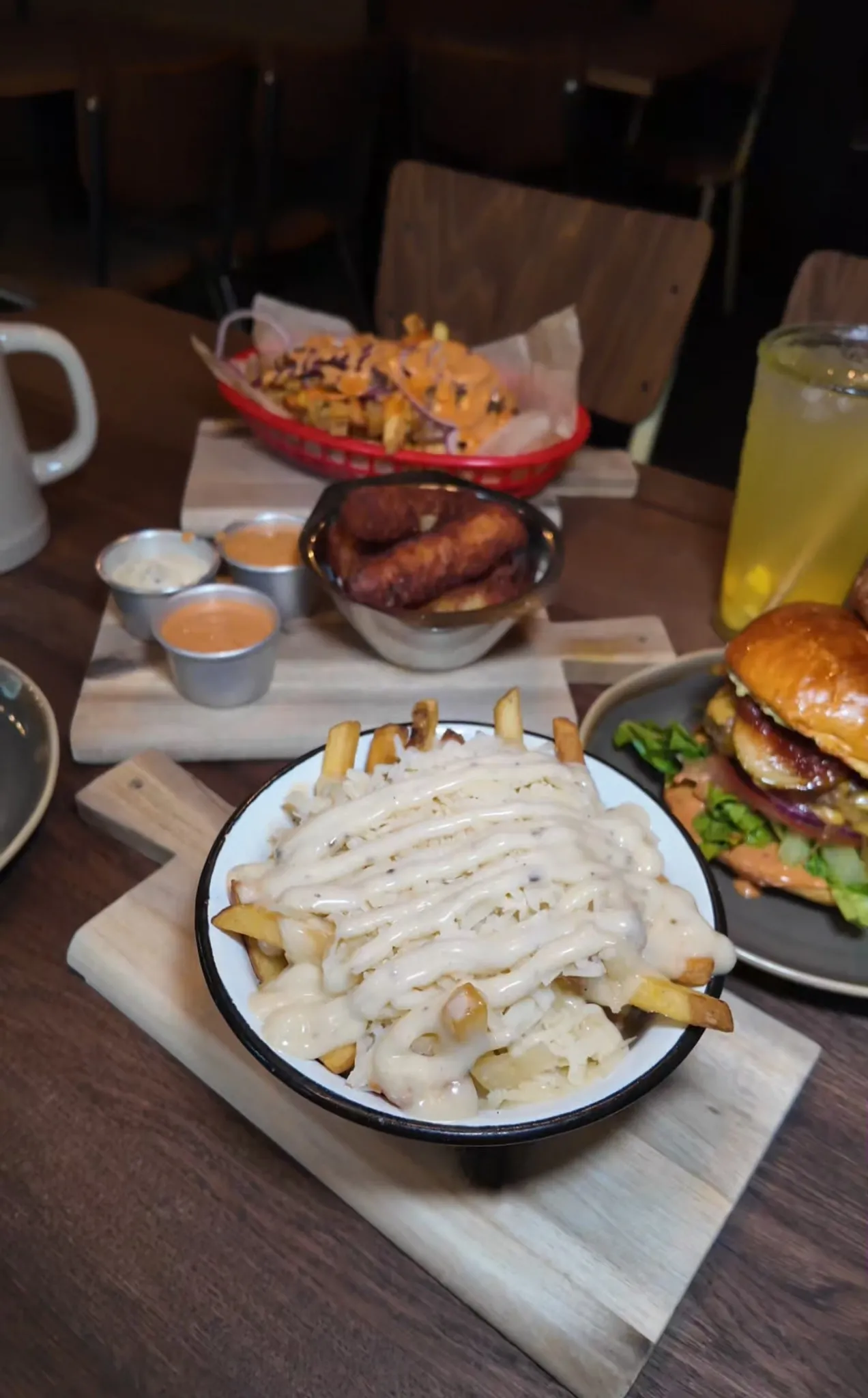 Tisch im Hornochse Köln reich gedeckt mit Burger, überbackenen Pommes mit Käsesauce, Onion Rings, Nachos und Dips – typische American Streetfood-Auswahl