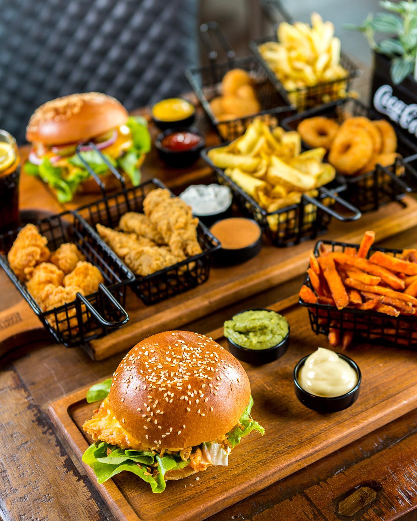 Reichhaltige Auswahl bei Monument Burger Leverkusen mit Burgern, Pommes, Süßkartoffelpommes, Onion Rings, Nuggets und Dips auf einem Servierbrett