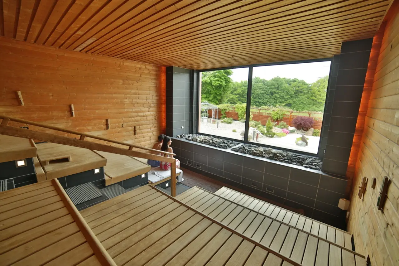 roße Panoramasauna im AQUALAND Köln mit Holzliegen und Blick ins Grüne durch ein großes Fenster