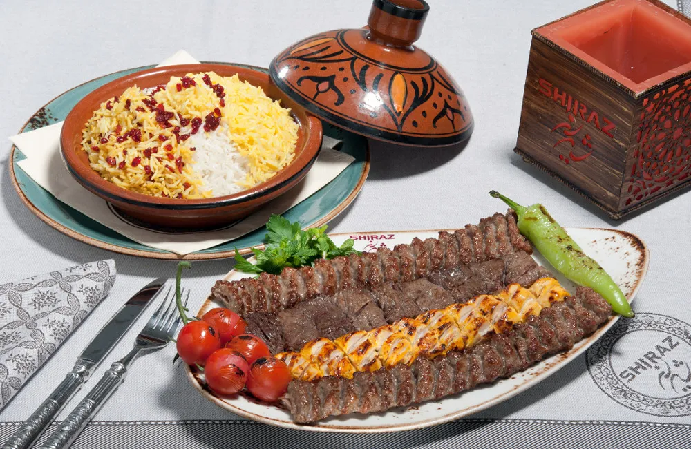 Persisches Grillgericht mit verschiedenen Kabab-Spießen, gegrillten Tomaten und Safranreis mit Berberitzen, serviert im Shiraz Restaurant Darmstadt
