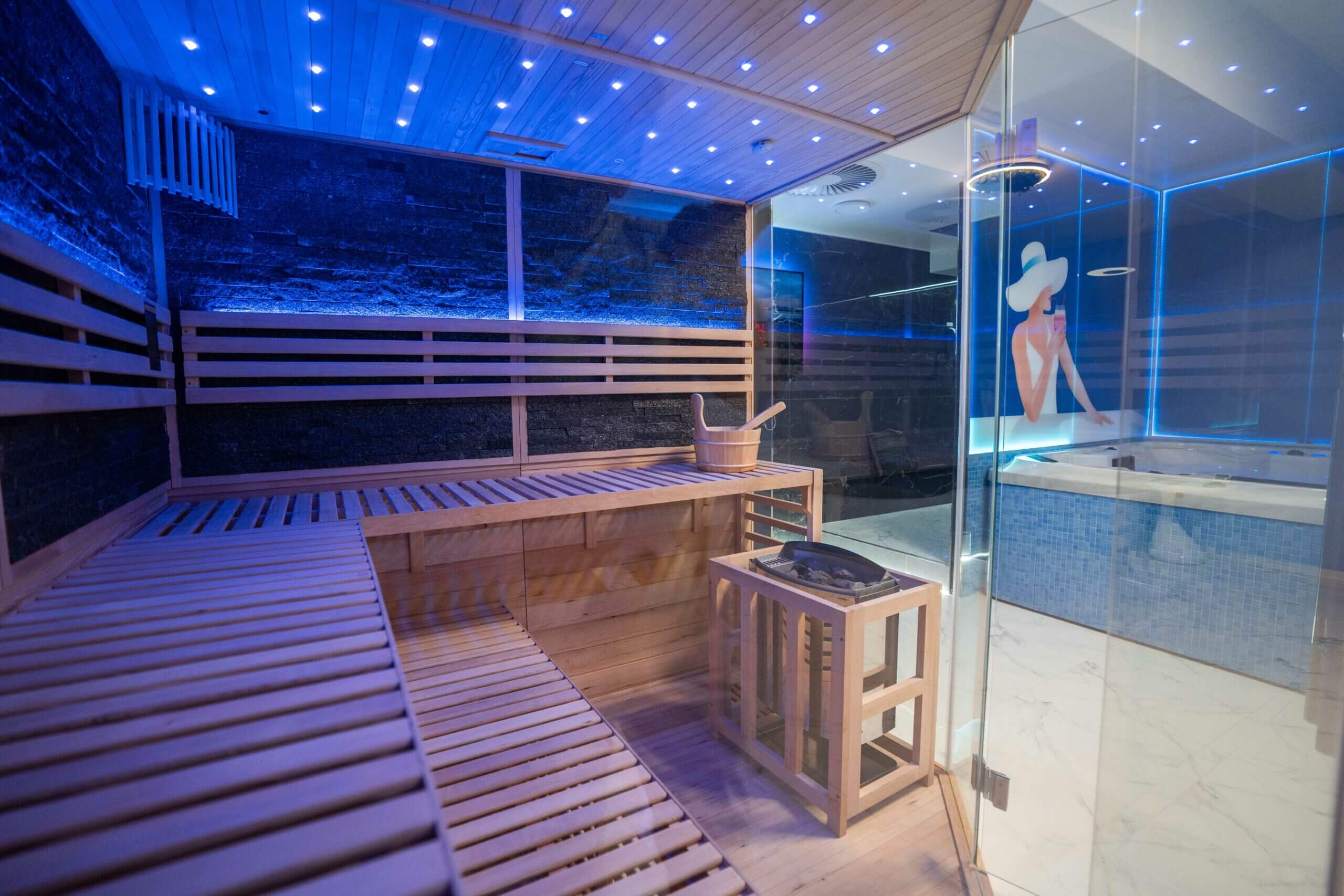 Moderne Infrarotsauna in der Wellness Lounge 20° Hanau mit Holzliegen, Glasfront und LED-Sternenhimmel, Ausblick auf den angrenzenden Whirlpoolbereich