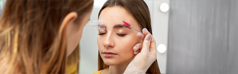 Frau bei einer Brow Lifting Behandlung mit Styling-Bürstchen und Folienabdeckung