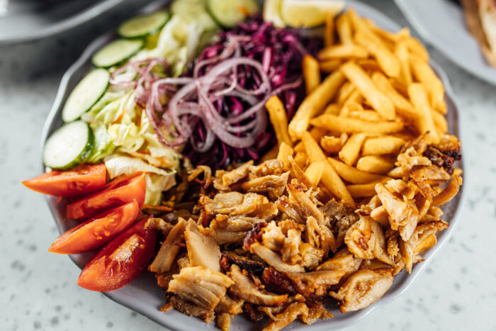Dönerteller mit knusprigem Fleisch, Pommes, frischem Salat und Gemüse