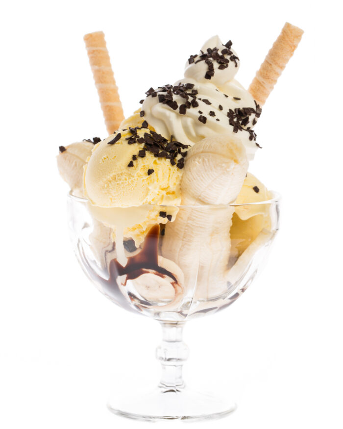 Klassischer Bananensplit mit Vanilleeis, Schokosoße, Sahne, Streuseln und Waffelröllchen