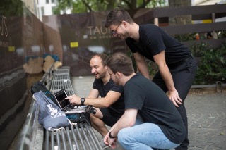 Drei Männer bei einer Outdoor-Rallye mit Laptop und Ausrüstung im Stadtgebiet Frankfurt