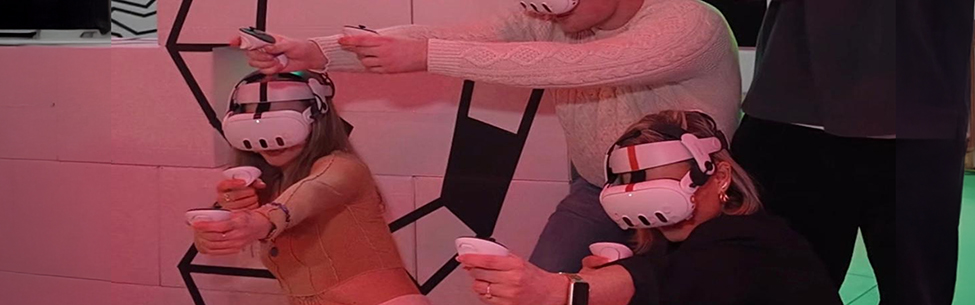 Gruppe von vier Personen spielt gemeinsam VR-Laser-Tag hinter Deckung in einer stylischen Arena in Berlin.