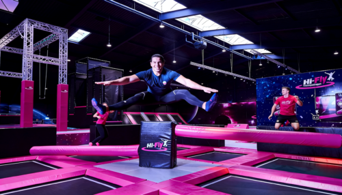 Person springt im HI FLY Trampolinpark Hilden über ein Hindernis – Indoor-Action mit Neonbeleuchtung und Trampolinflächen
