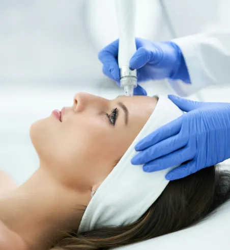Frau erhält eine Hydrafacial-Gesichtsbehandlung durch eine Fachkraft mit Handschuhen