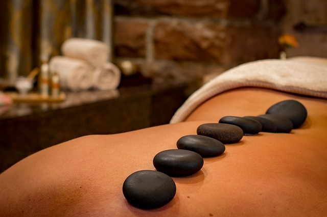 Hot-Stone-Massage mit schwarzen Lavasteinen in einer stimmungsvollen Wellnessumgebung